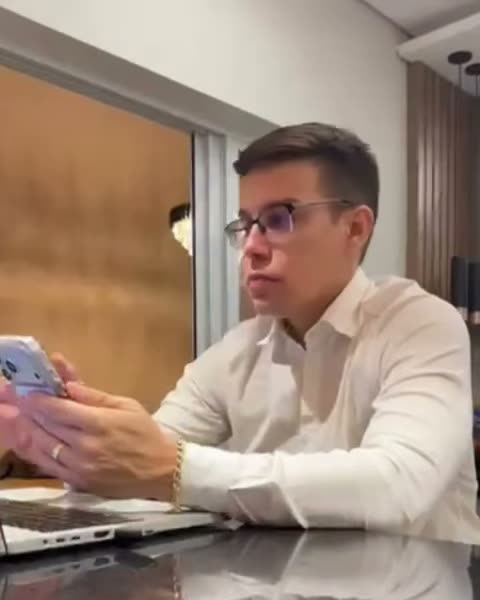 Dr. Alisson ao telefone no escritório, de camisa branca